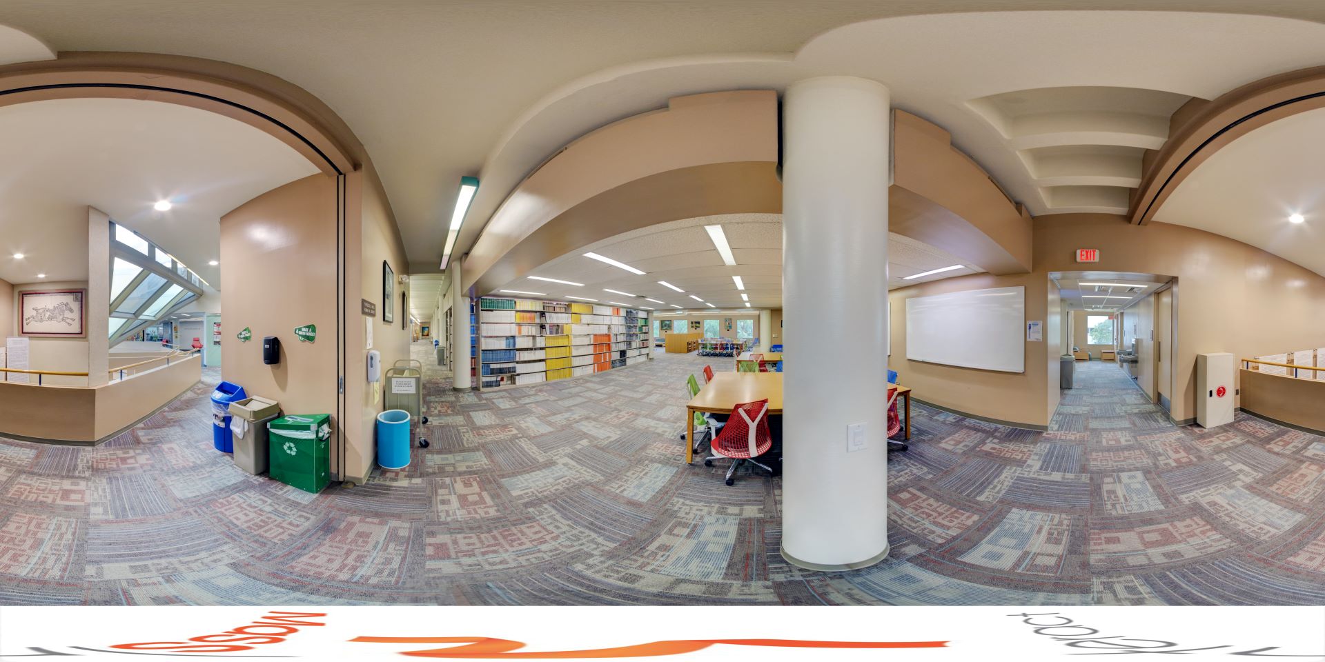 Panoramic view of the second floor in Evans Library, featuring an open study area with bookshelves, tables, and a recycling station
